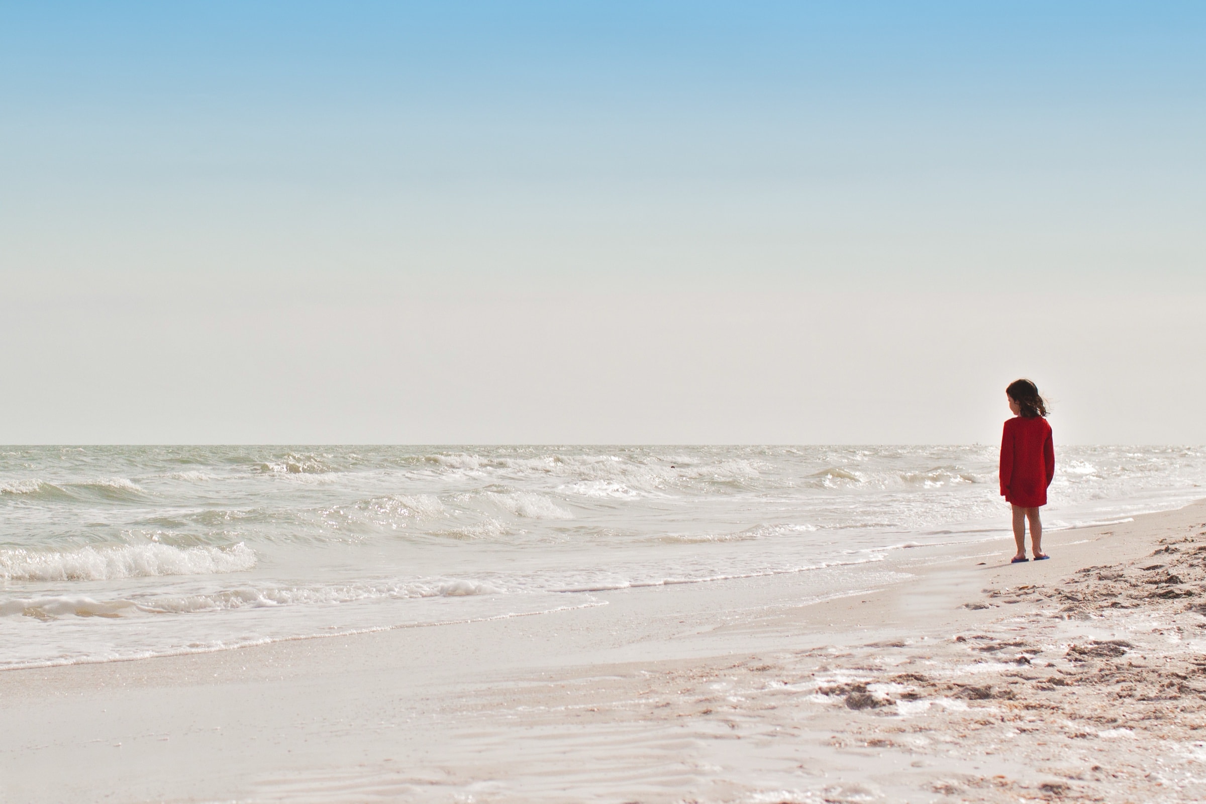 A small child standing alone at the edge of the sea