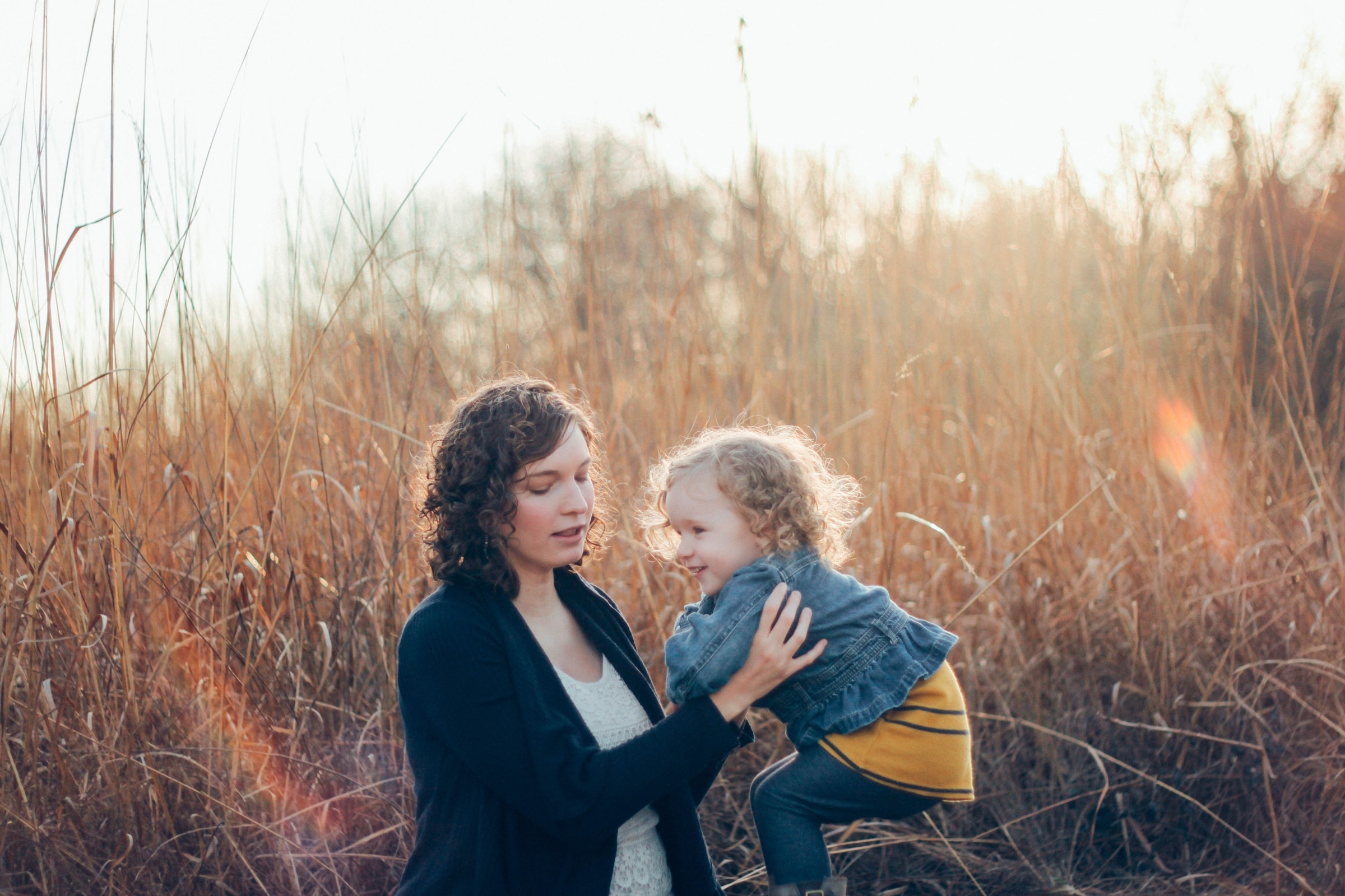 A mother and her toddler face to face in a field