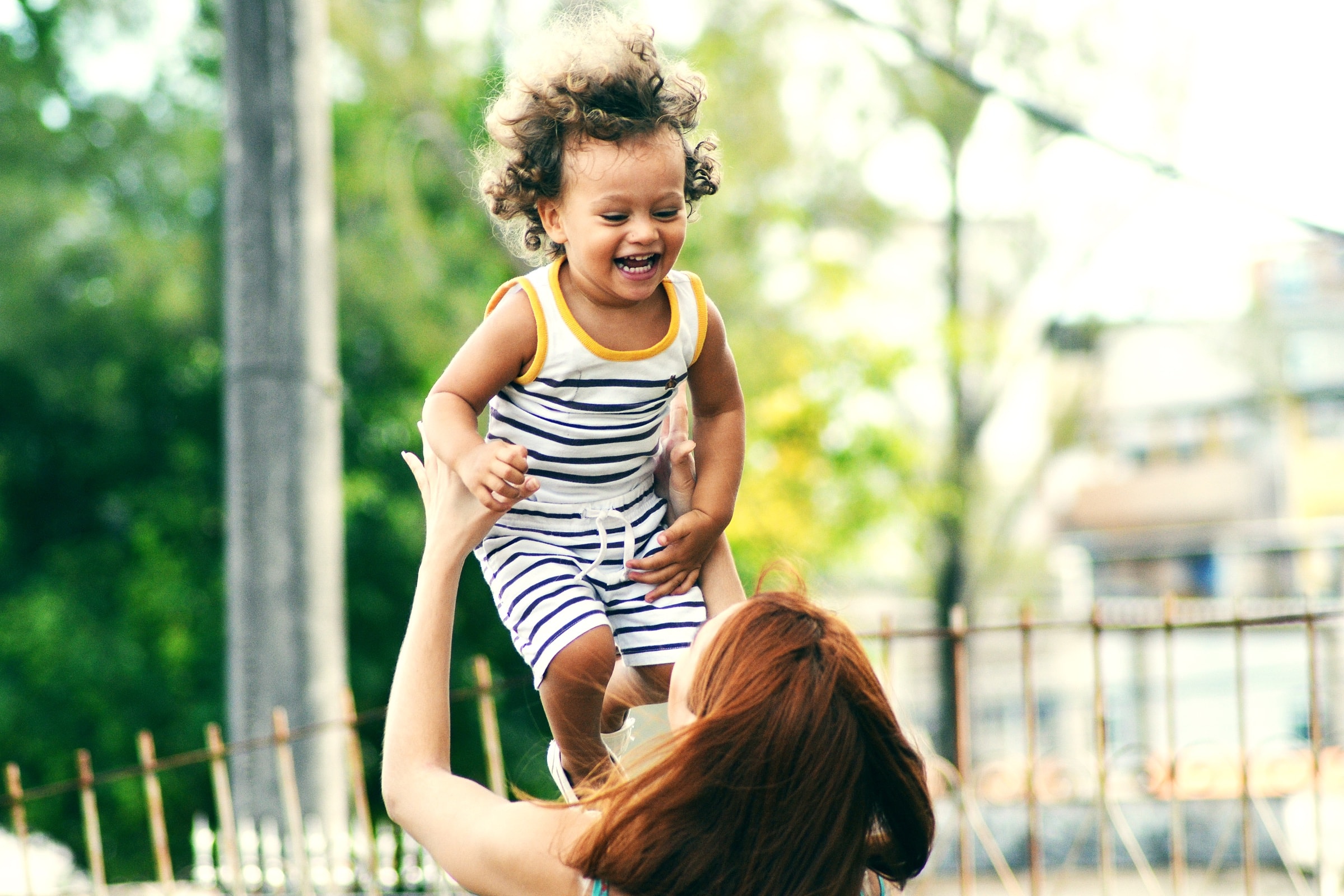 A mother lifting her laughing toddler into the air