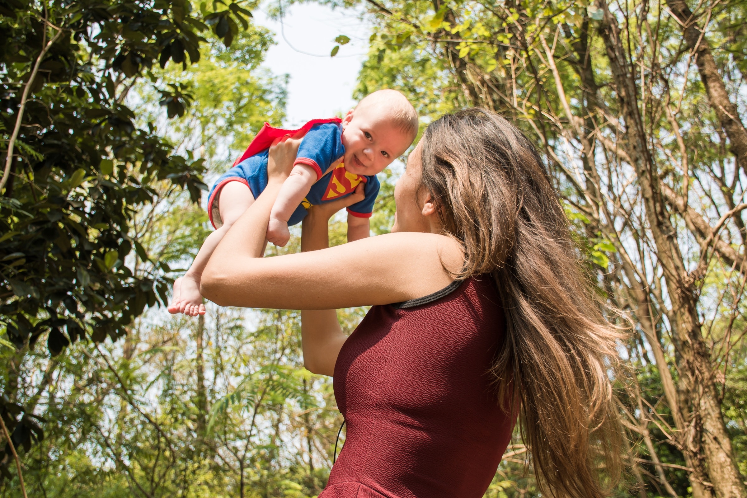 A mother lifting her baby into the air outdoors