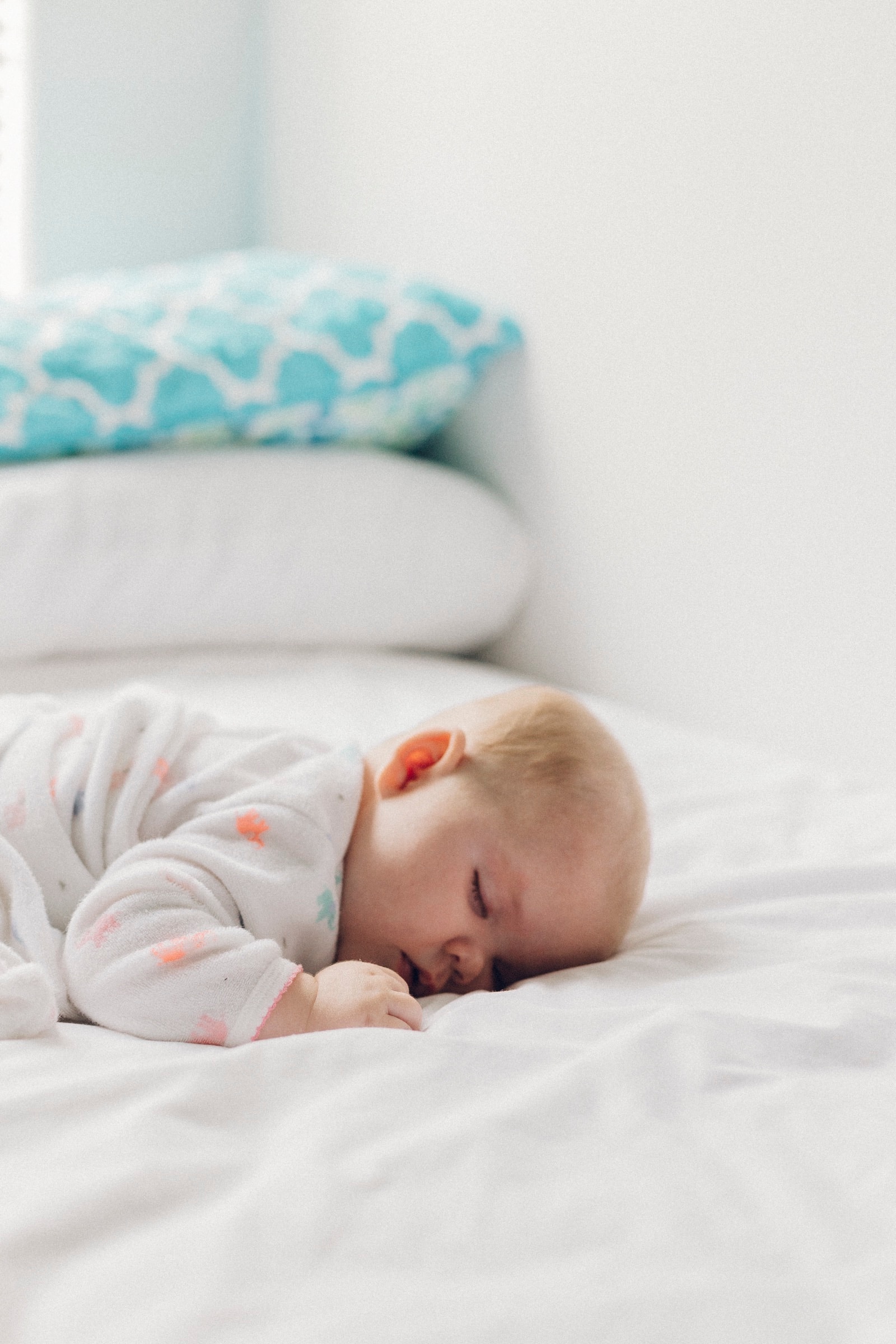 Baby sleeping peacefully on a white bed