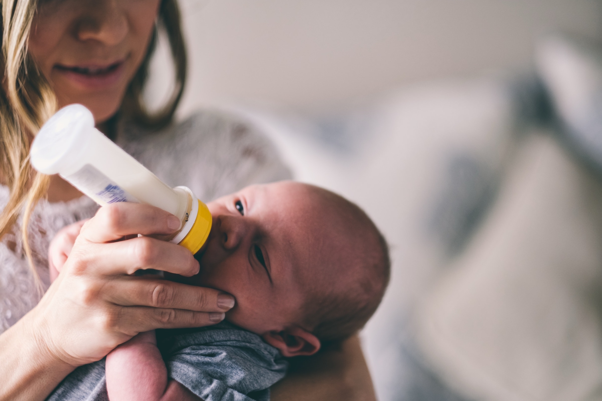 A baby taking a bottle in a parent's arms