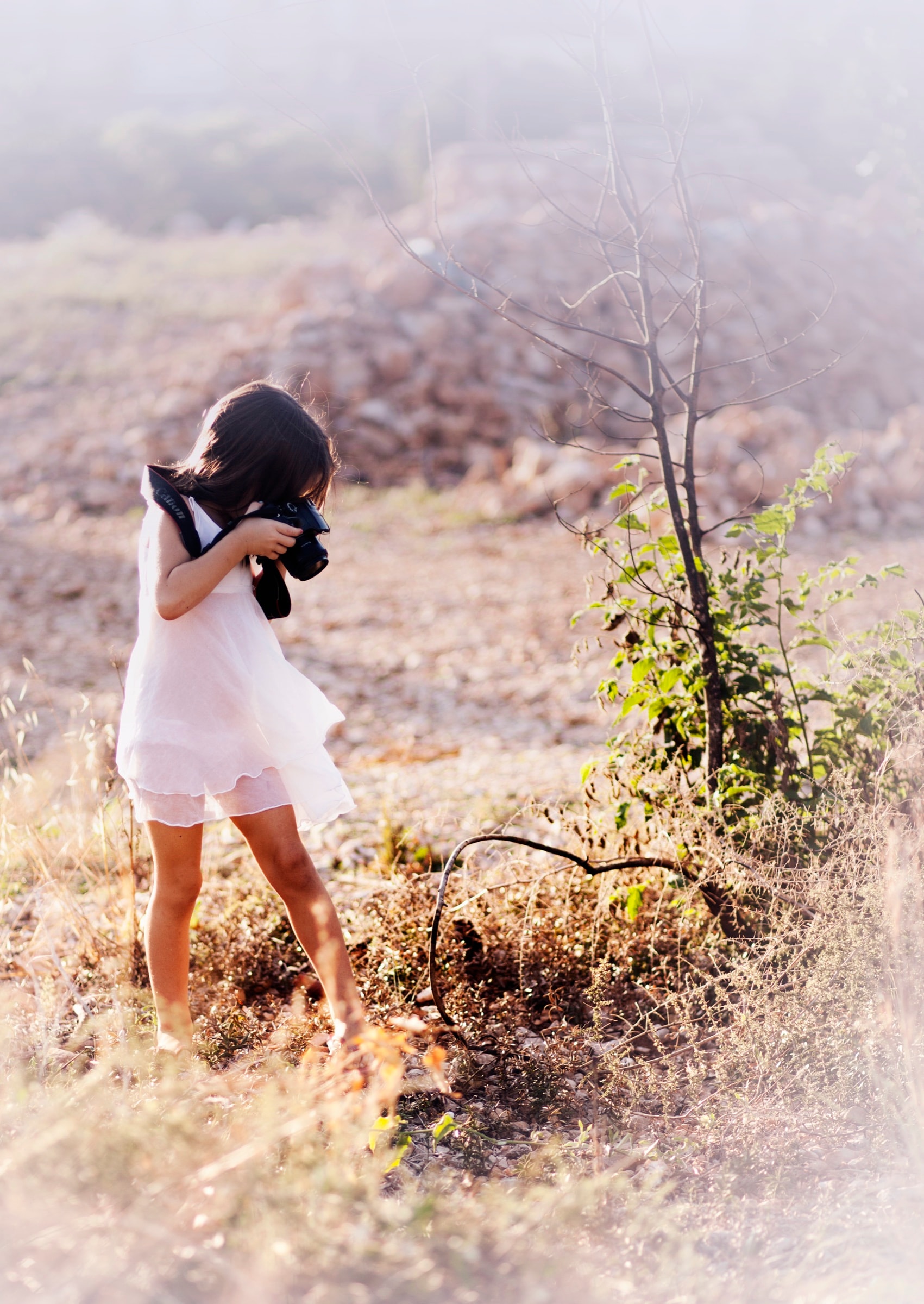 A child holding a camera up outdoors