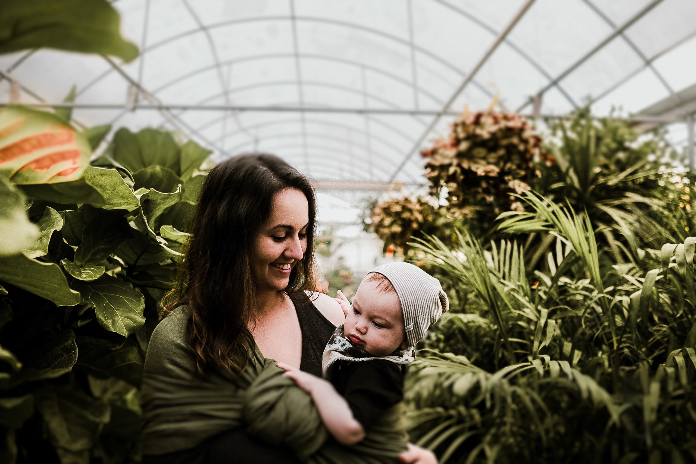 A mother holding her baby, surrounded by green plants