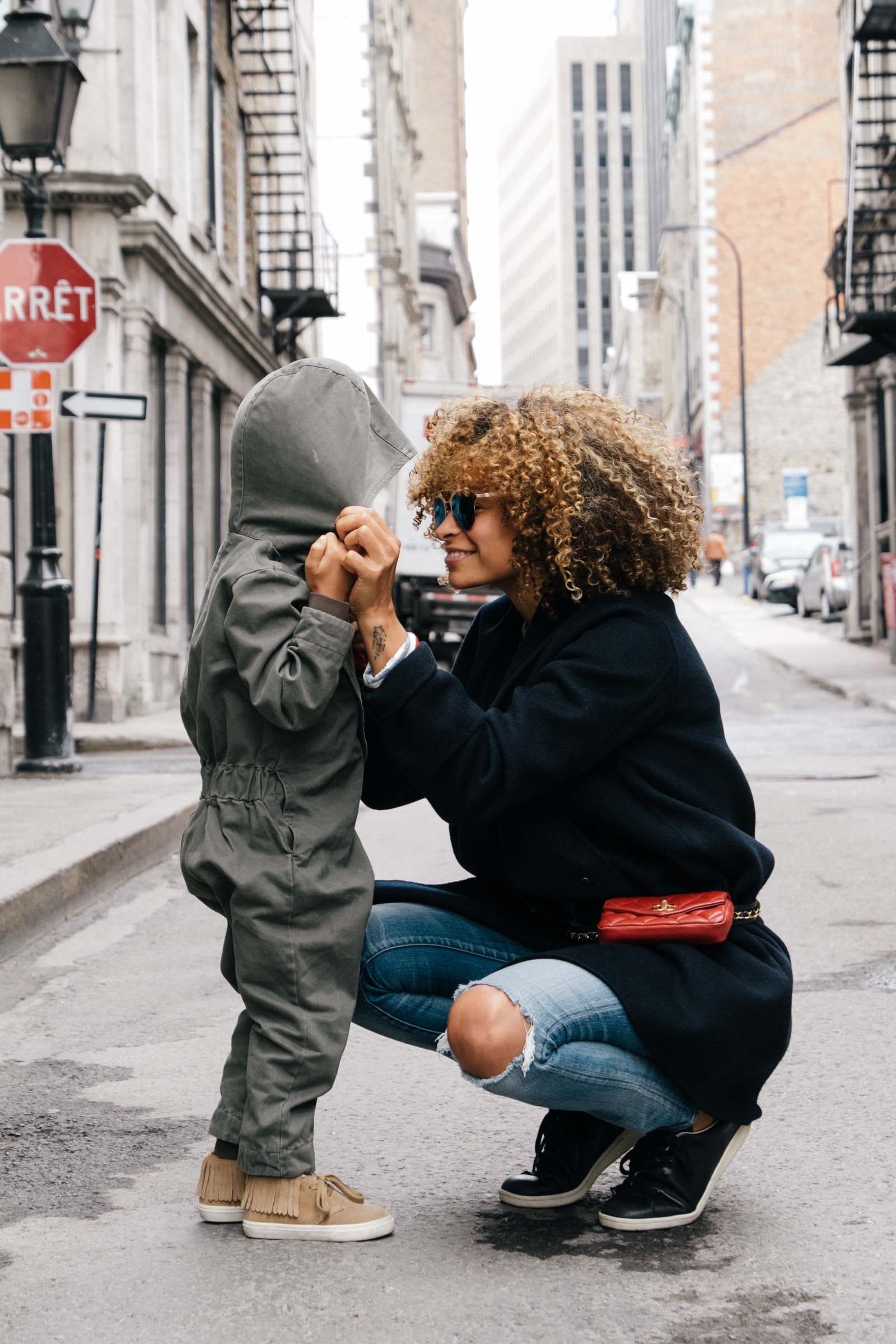 A parent crouching down to talk to their toddler outdoors