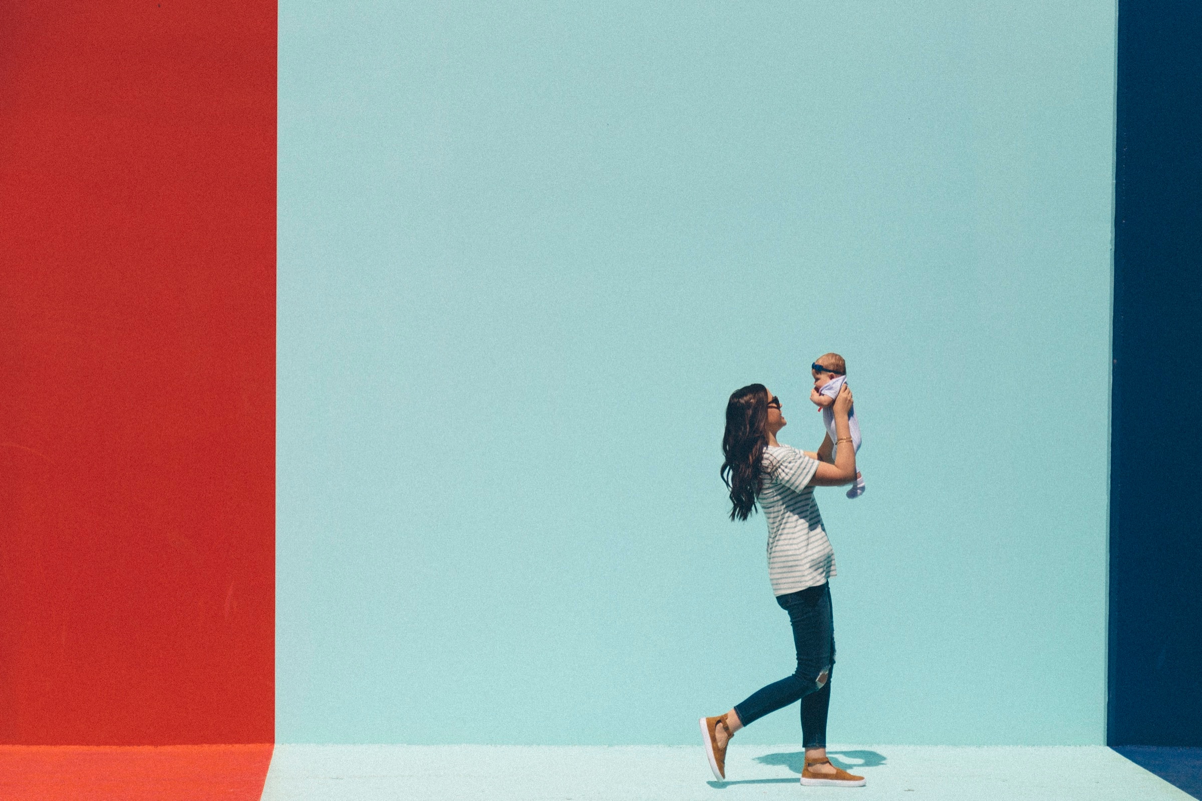 A parent lifting their baby against a brightly painted wall