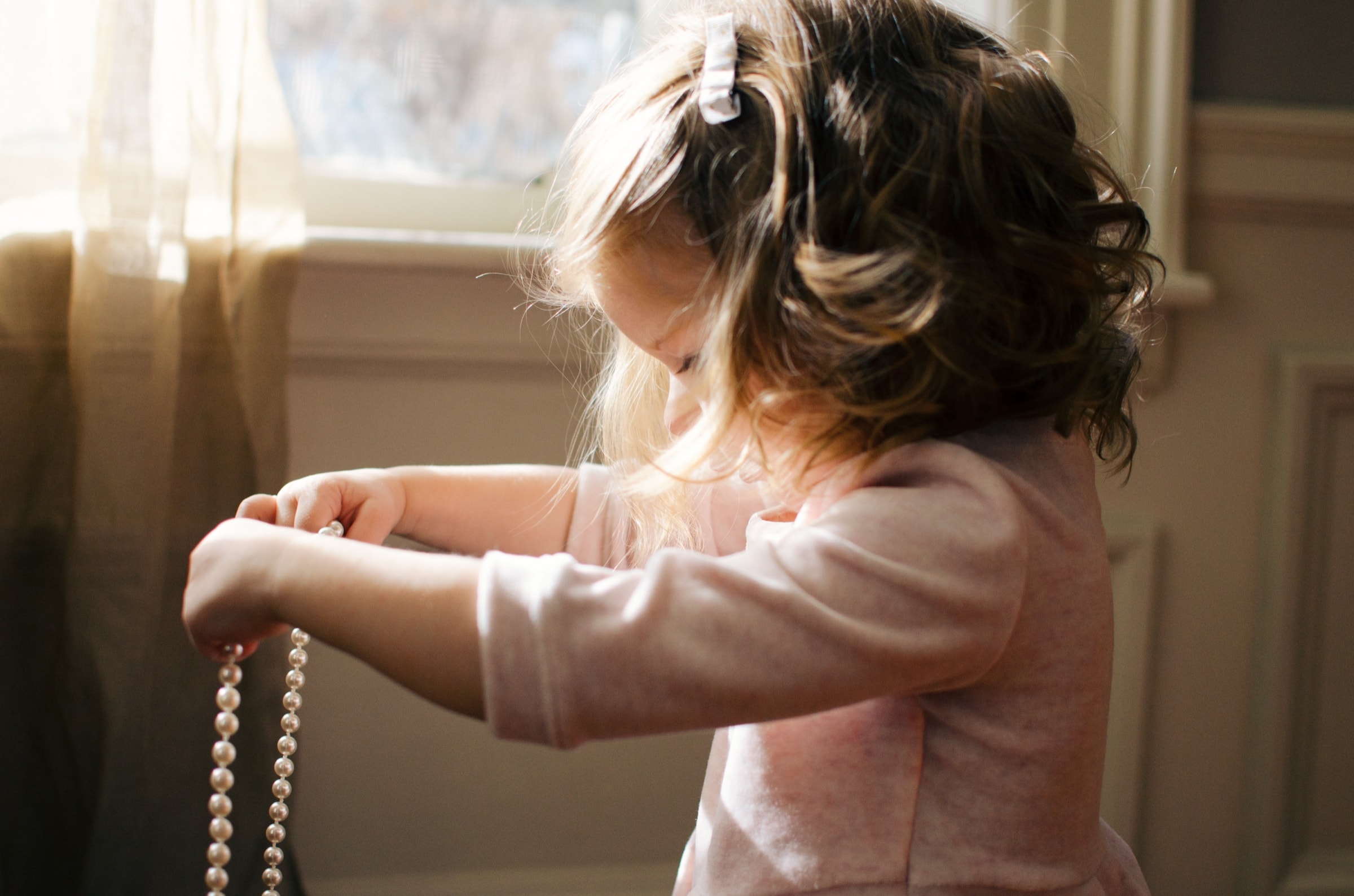 A toddler playing by a window in warm afternoon light