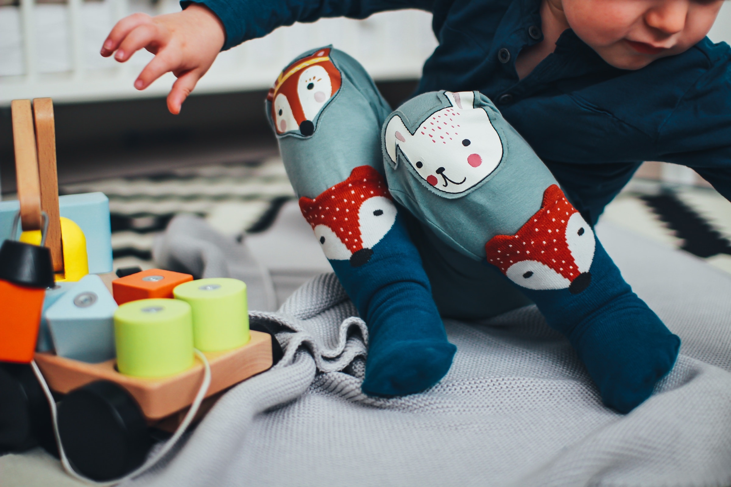 A toddler sitting on the floor among wooden toys