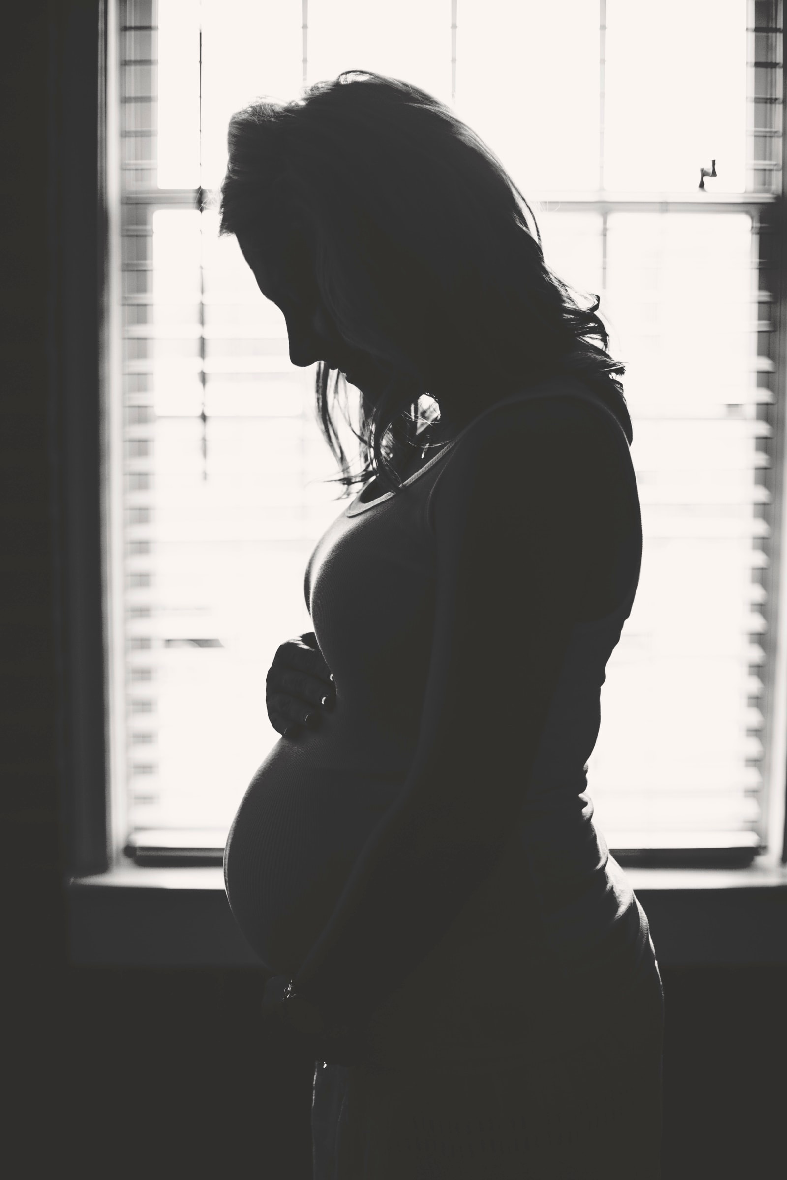 Silhouette of a pregnant woman by a window